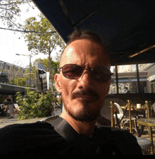 a man wearing sunglasses stands in front of a mcdonalds