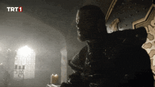 a man with a beard is sitting in a dark room with trt1 written on the bottom