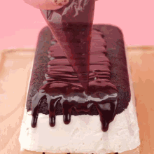 a person is pouring chocolate icing on a chocolate cake