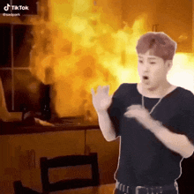 a man is standing in front of a kitchen with fire coming out of it .