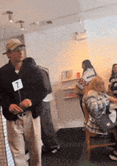 a man wearing a number 7 sign stands in a room