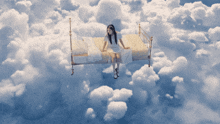 a girl is sitting on a bed in the clouds
