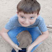 a young boy sitting on the ground holding a cell phone with a screen that says ' samsung ' on it