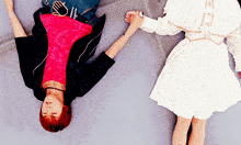 a woman in a white dress holds the hand of a man laying on the ground