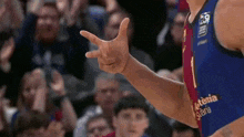 a basketball player is giving a peace sign in front of a crowd of people .