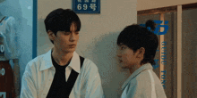 two young men are standing next to each other in front of a sign that has the number 69 on it