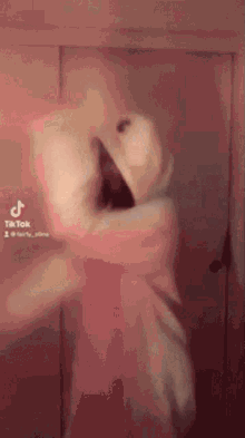 a person is standing in front of a door in a room with a pink background .