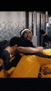 a man wearing a headband with nike on it is hugging another man in a huddle
