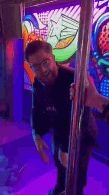 a man with glasses is standing on a pole in a room with a painting on the wall .