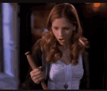 a woman in a white shirt is holding a wooden stick