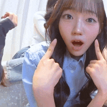a girl with a surprised look on her face is pointing her fingers up