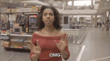 a woman in a red top is standing in a mall and says omg