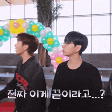 two young men are standing in front of balloons and one of them is wearing a black sweatshirt that says r.o.p.