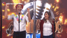 a man and a woman are standing in front of a microphone with eltrecetv.com written on the bottom