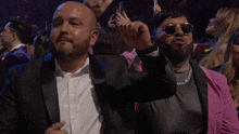 a man in a suit and sunglasses stands in a crowd