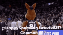 a coyote mascot is standing in front of a crowd at a basketball game .