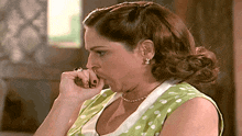 a woman wearing a green and white polka dot dress is covering her mouth with her hand