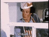 a man wearing a hat and apron is standing in front of a window and says woah ...