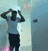 a man in a white shirt and black pants is dancing in a hallway