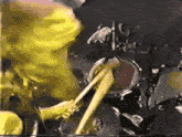 a man in a yellow shirt is playing a drum