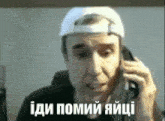 a man wearing a white hat is talking on a cell phone with a caption in another language