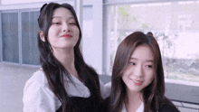two young women are posing for a picture and smiling for the camera