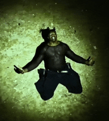 a man in a black shirt is kneeling down on the ground with his arms outstretched
