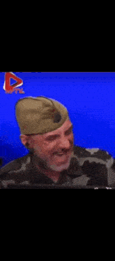 a man in a military hat is laughing in front of a blue screen .