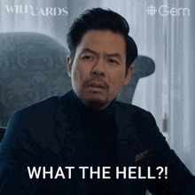 a man in a suit and black turtleneck says what the hell