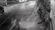 a group of people are standing on the side of a street at night .