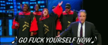 a man in a suit and tie is standing in front of a group of gospel singers with the words go fuck yourself now above them