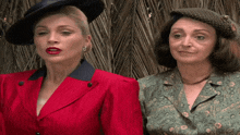 a woman in a red jacket stands next to a woman in a green shirt