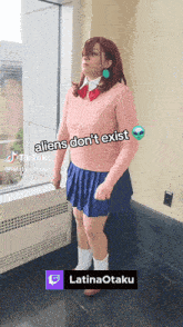 a woman in a pink sweater and blue skirt stands in front of a window with the words aliens don t exist