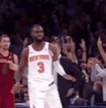 a basketball player wearing a white jersey with the number 3 on it is standing on a court .
