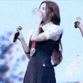 a woman in a school uniform is singing into a microphone while standing on a stage .