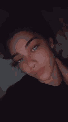 a woman with a nose ring and earrings is looking at the camera