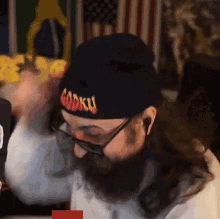 a man with a beard wearing a black beanie that says godku on it