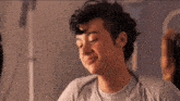 a young man with curly hair is smiling and looking down