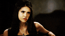 a woman wearing a black dress and a silver necklace with a skull on it