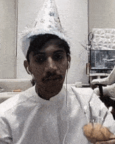 a man wearing a party hat is holding a cupcake