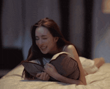 a woman is laying on a bed holding a pillow