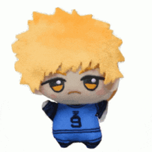 a stuffed toy with yellow hair and a blue shirt that says ' x ' on it