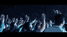 a man with a beard is standing in front of a crowd with his arms in the air
