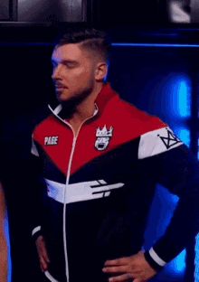 a man wearing a red , white and black jacket with a crown on it is standing in a dark room .