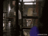 a man in an apron is standing in front of a window with a gif run.com watermark