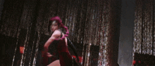 a woman in a red dress is fighting a giant spider