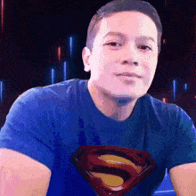 a man wearing a blue shirt with a superman logo