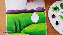 a person is painting a landscape with drawbook written below it