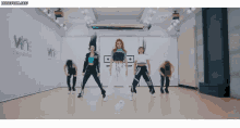 a group of women are dancing in a dance studio with a sign that says wine entertainment