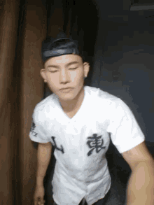 a young man wearing a baseball cap and a white shirt with chinese characters on it .